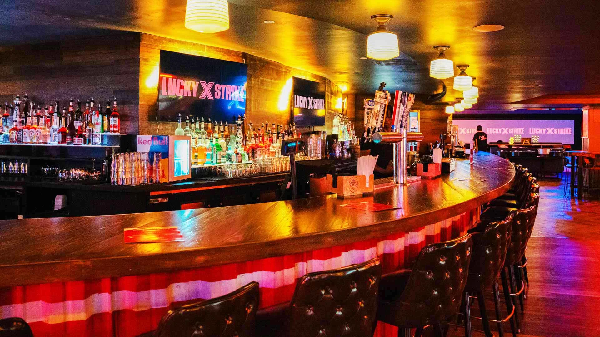 Lucky Strike full-service bar with high-top seating, draft taps, and backlit liquor display.