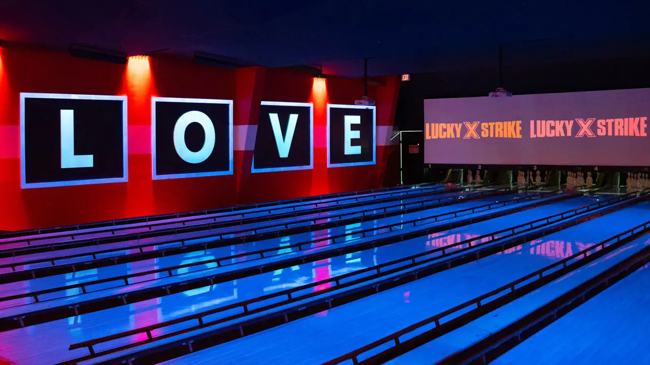 Beautiful bowling lanes with black lights and large TV screens above the lanes.