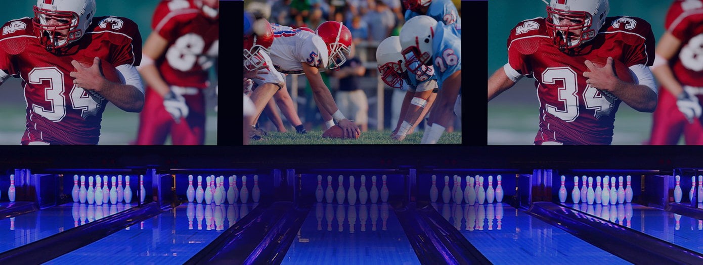 Football being displayed on screens above bowling lanes