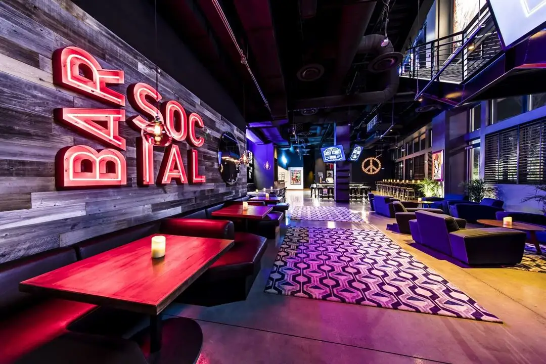 Lucky Strike social lounge with neon bar sign, booth seating, patterned rug, and a lively upscale nightlife atmosphere.