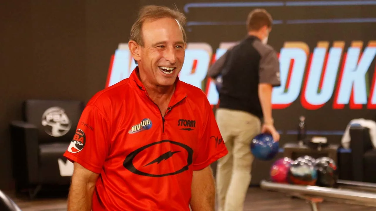 Image of professional bowler Norm Duke smiling in front of the lanes at a bowling center.