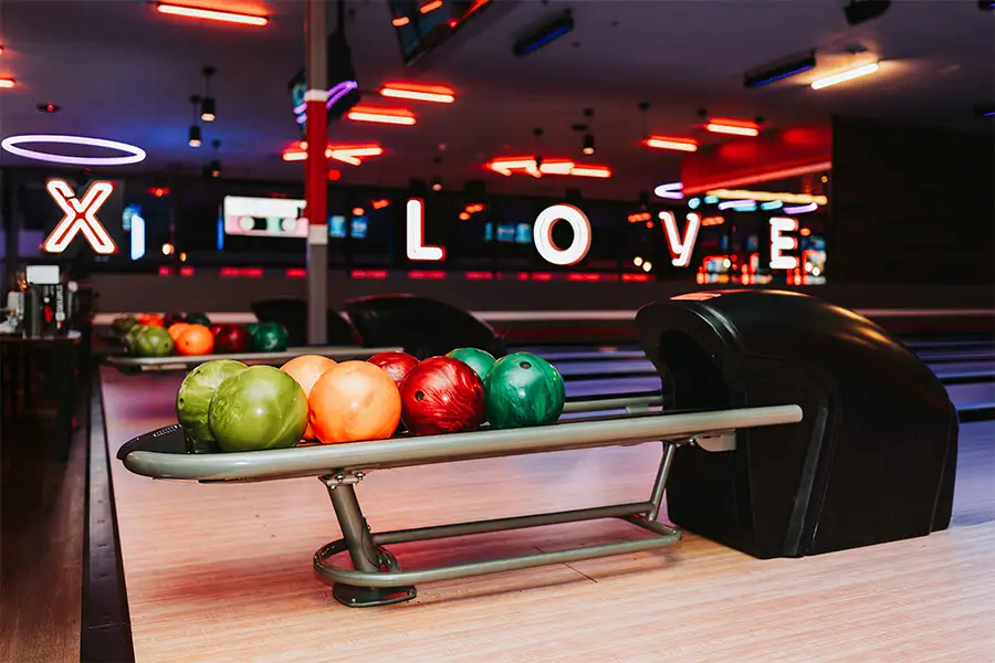 Colorful bowling ball on return rack with bowling center in the background