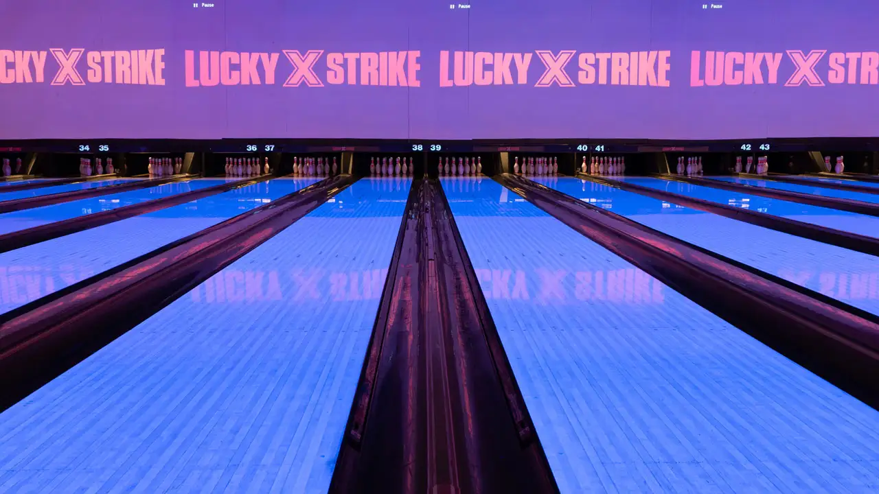 Beautiful bowling lanes with black lights and large TV screens above the lanes.