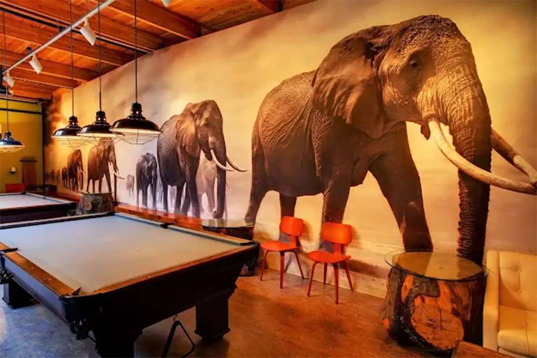 Rows of pool tables inside a spacious hall with large industrial lights.