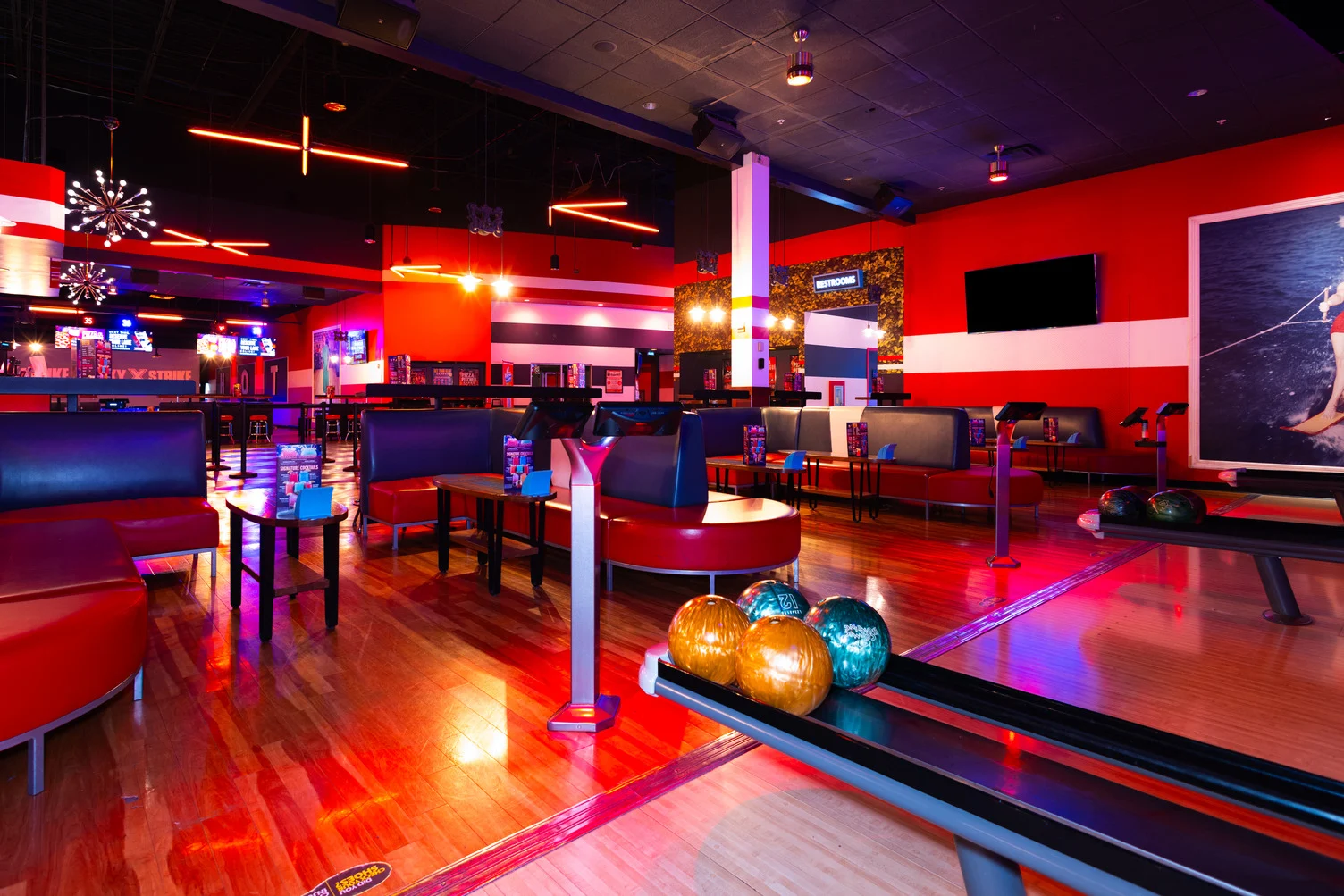 Lane approaches at Lucky Strike Algonquin with lounge seating, ball return machines, tables and neon lights.