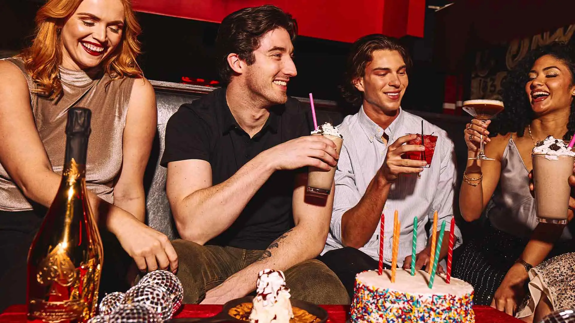 Friends celebrating birthday with cake and drinks at Lucky Strike.