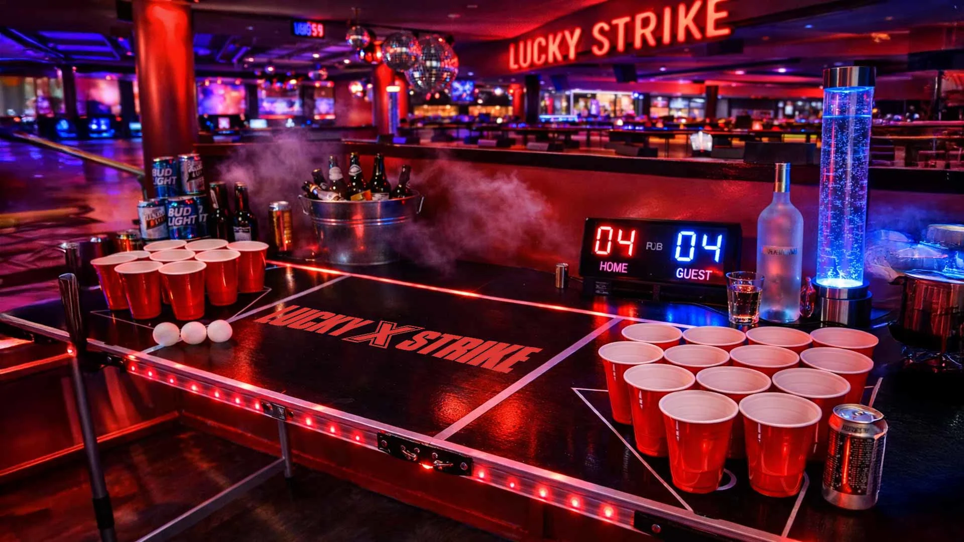 LED-lit beer pong table with Lucky Strike branding set inside a neon-lit Lucky Strike bowling and entertainment venue.