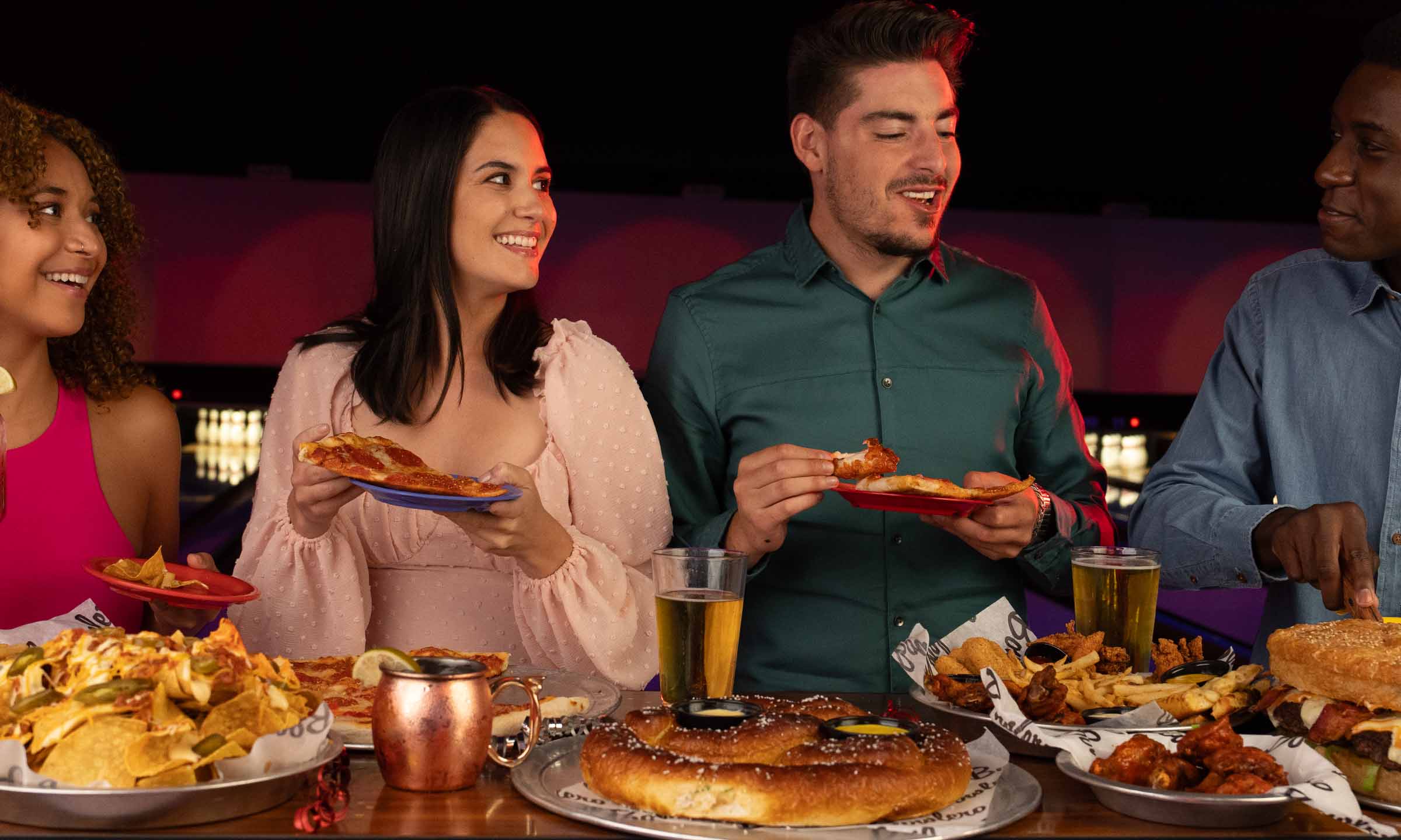Group of people enjoying pizza, wings, french fries, and nachos