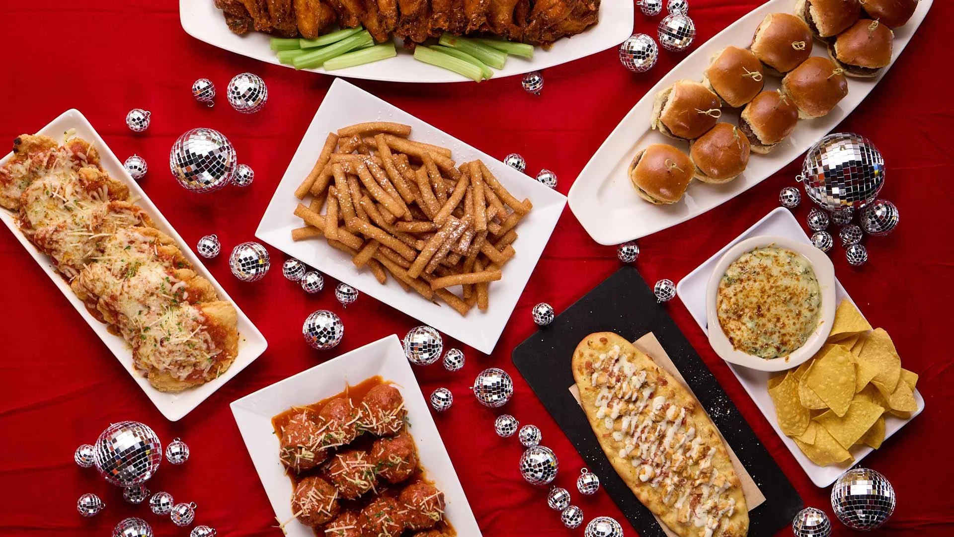 Premium catered event spread with appetizers, flatbreads, and shareable plates on a red tablecloth.