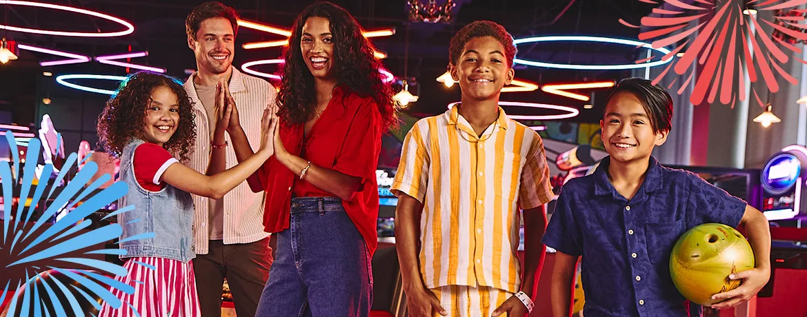 Two adults and three kids smiling and having fun at a bowling center for the 4th of July.