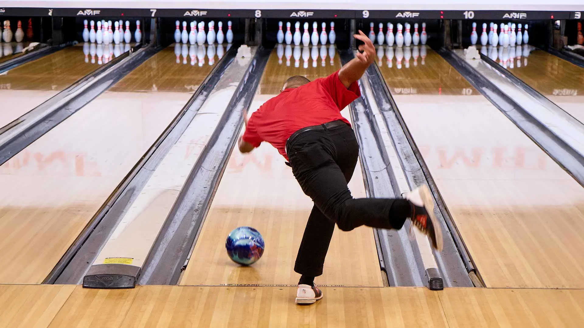 Bowler releasing a bowling ball toward pins during a competitive league game at AMF lanes