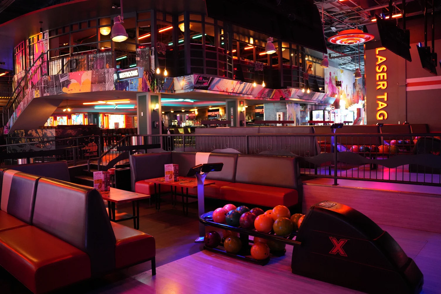 Large room in a bowling alley with lots of seating and second floor