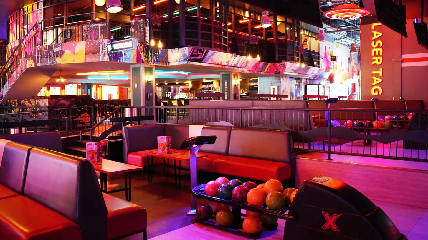 Modern Lucky Strike entertainment venue featuring bowling lanes, lounge seating, and laser tag area with vibrant neon lighting.