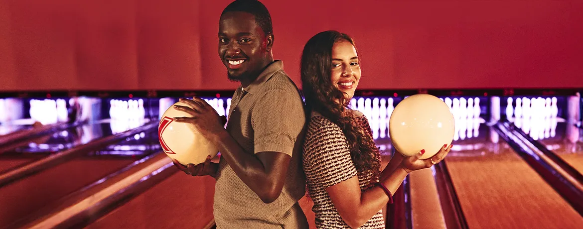 Two bowlers standing back-to-back in front of bowling lanes