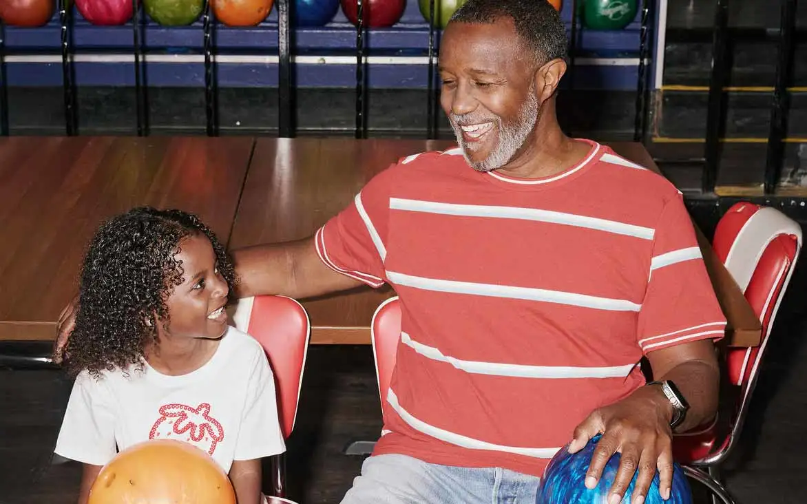 Father and young daughter laughing together while bowling at AMF