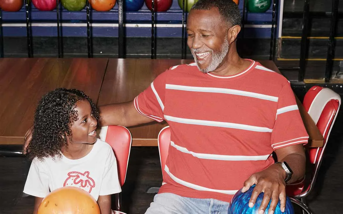 Father and young daughter laughing together while bowling at AMF