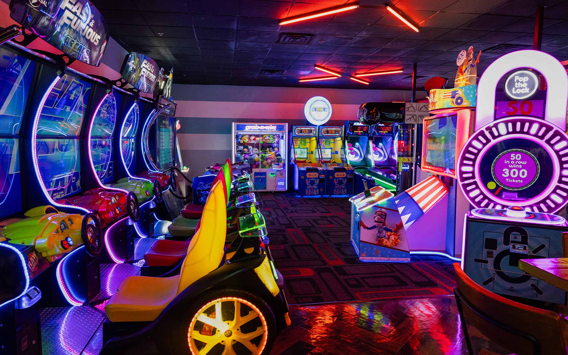 Colorful arcade at Lucky Strike featuring racing games, ticket machines, and neon lighting for a high-energy gaming experience.