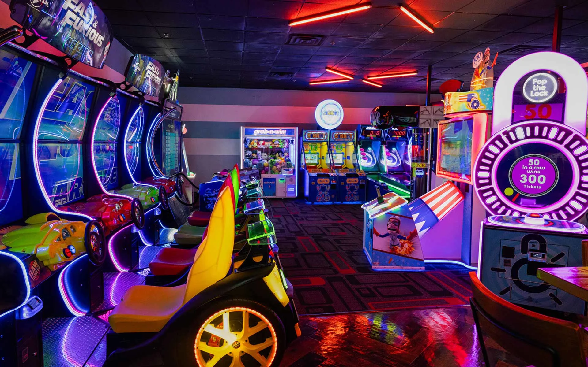 Colorful arcade at Lucky Strike featuring racing games, ticket machines, and neon lighting for a high-energy gaming experience.
