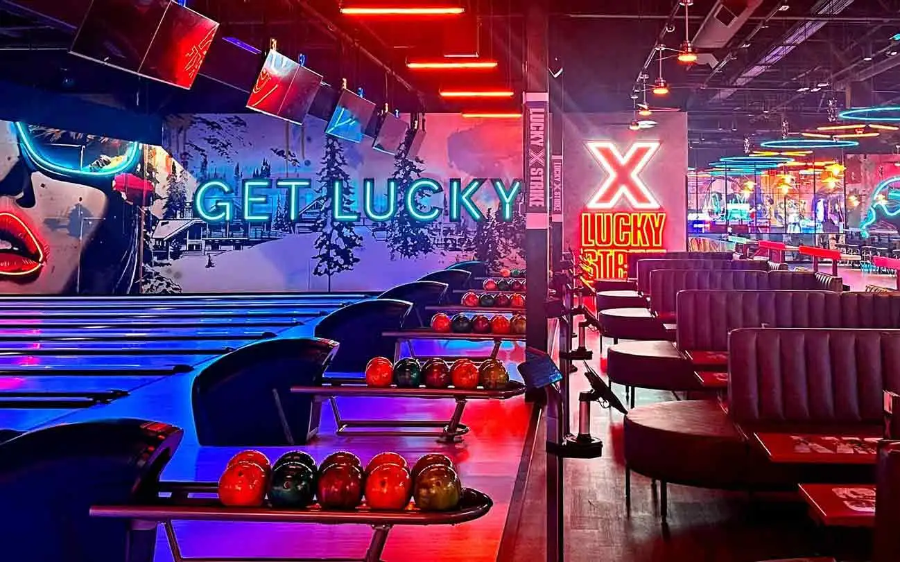 Bowling lanes with Get Lucky neon wall mural and Lucky Strike branded signage at Lucky Strike Southlands