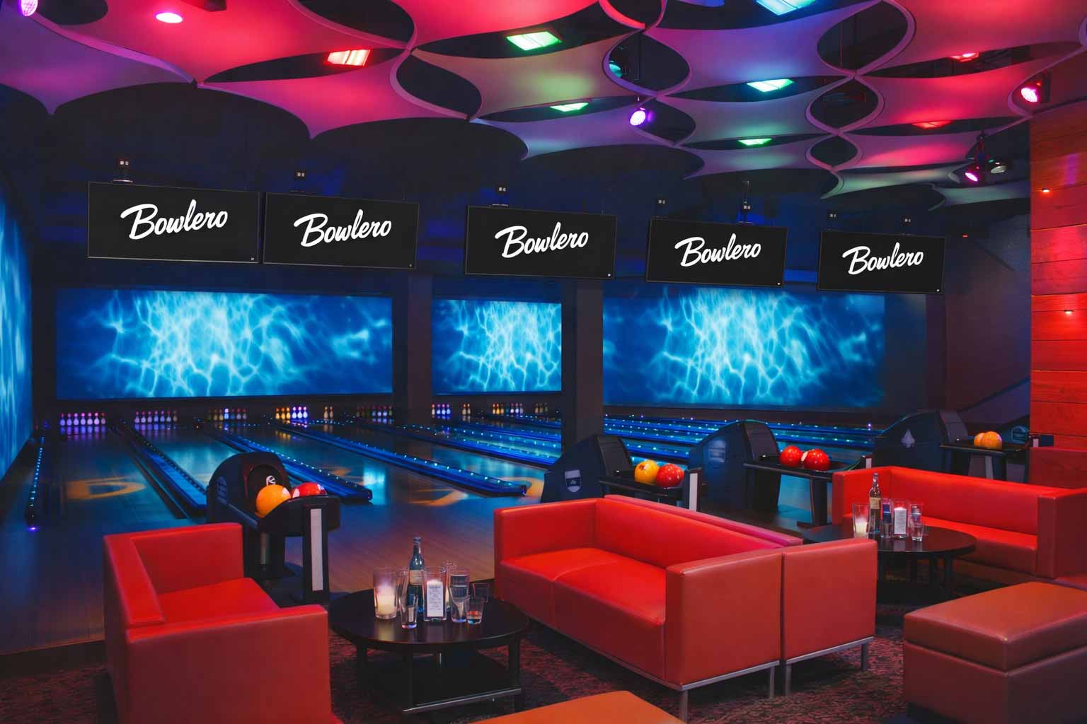 Upscale bowling lounge at Bowlmor Lanes featuring neon-lit lanes, modern lounge seating, and large overhead scoring screens.