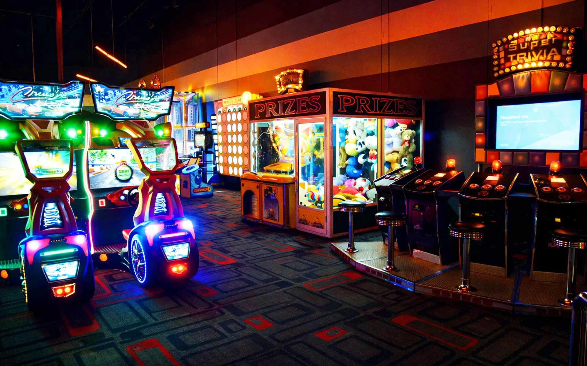 Modern arcade floor with glowing game machines and neon lighting near a laser tag area in a high-energy Lucky Strike entertainment venue