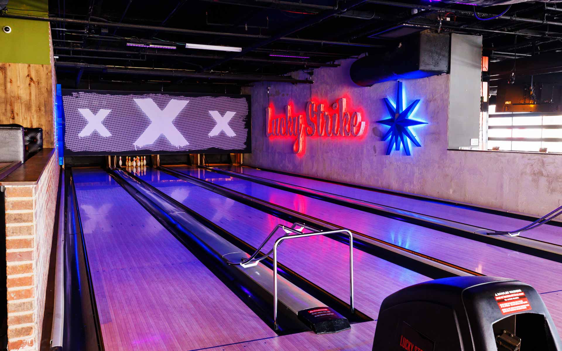 Sleek lanes with bold “Lucky Strike” neon signage and polished surfaces. The lighting and branding create a modern, nightlife-inspired bowling environment.