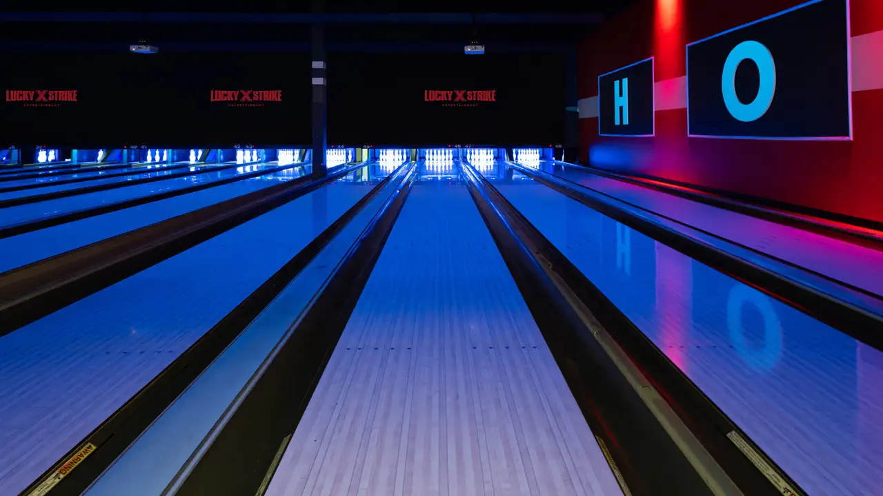 Beautiful bowling lanes with black lights and large TV screens above the lanes.