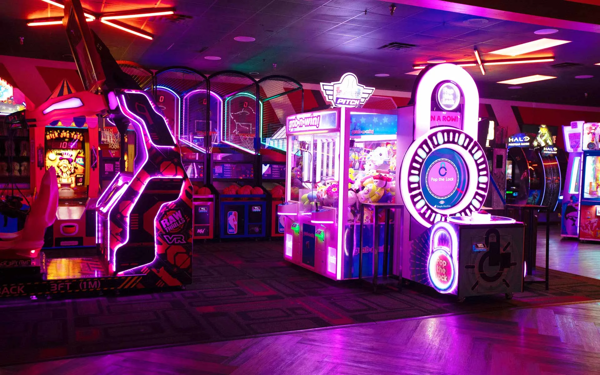 Lucky Strike arcade with neon lighting, VR gaming station, basketball games, and prize machines in a modern entertainment venue.