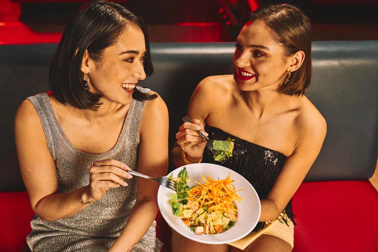 Two women eating dinner holding plates.