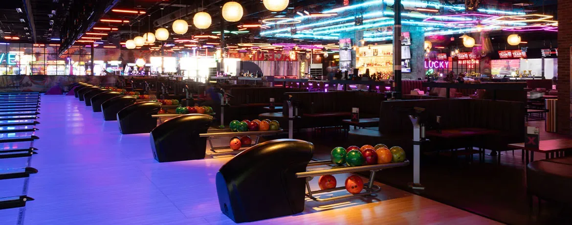 Beautiful bowling center with blacklight lanes and a neon-lit bar in the background