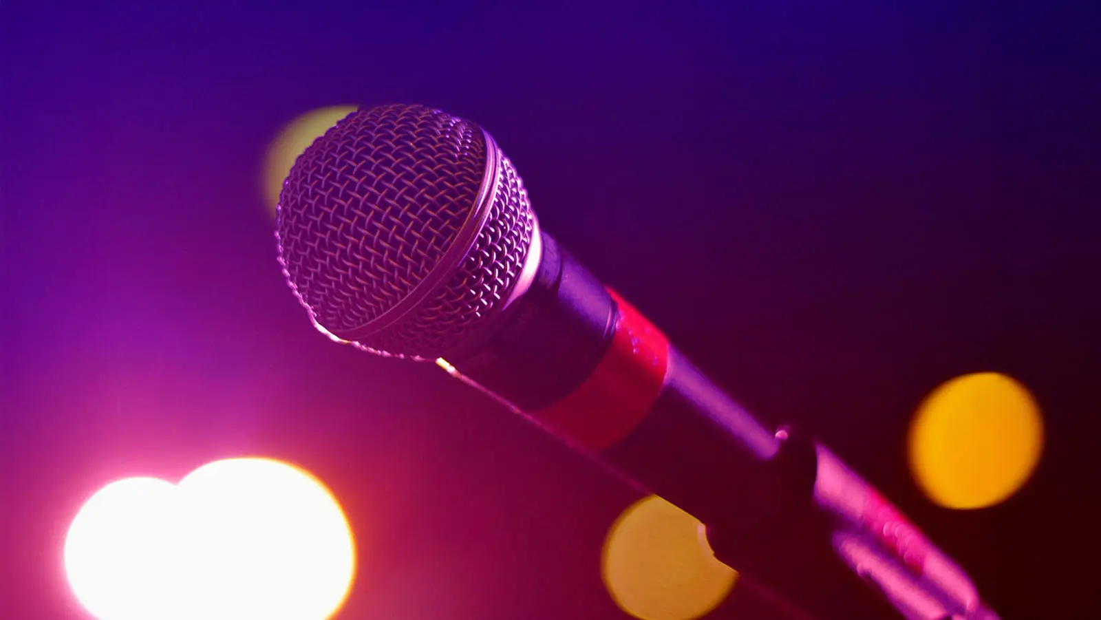 Close up of a microphone with stage lighting in the background