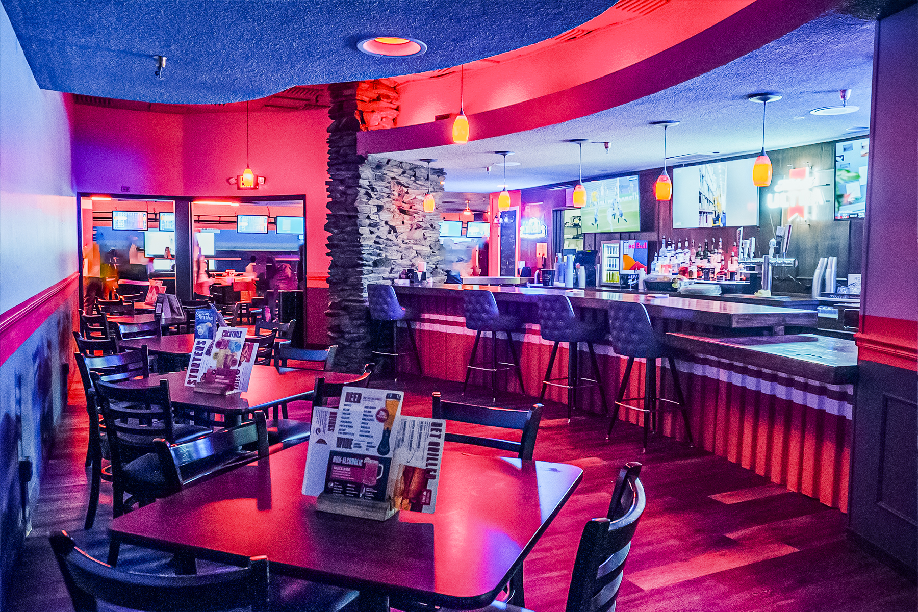 Unique, colorfully lit bar with TVs above the bar