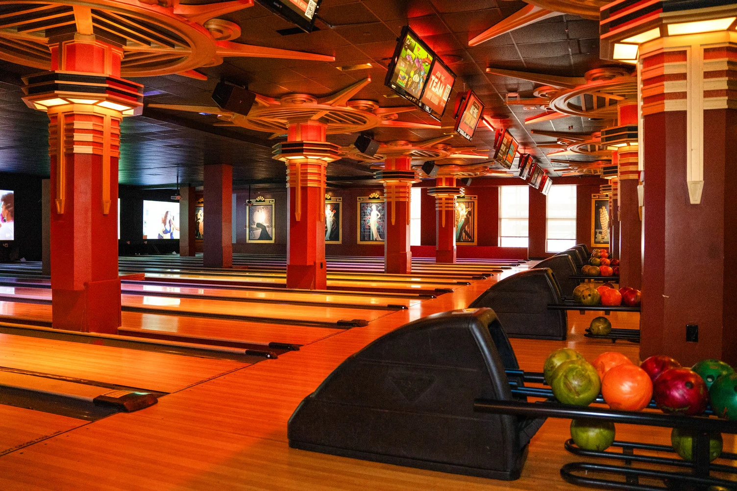 Wide view of bowling lanes at Lucky Strike Times Square featuring Art Deco columns, warm amber lighting, and overhead scoring screens