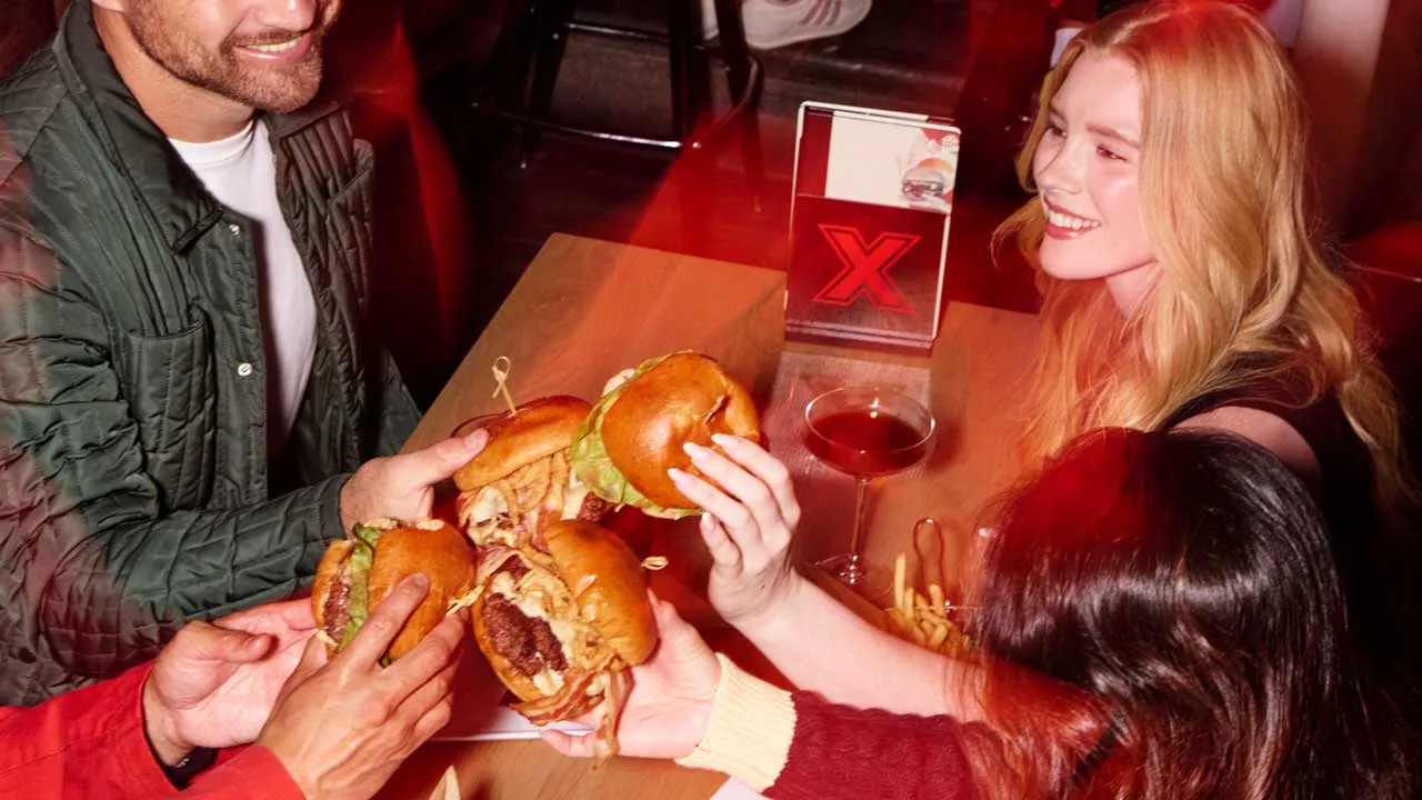 Friends at a table at a Lucky Strike bowling center eating burgers.