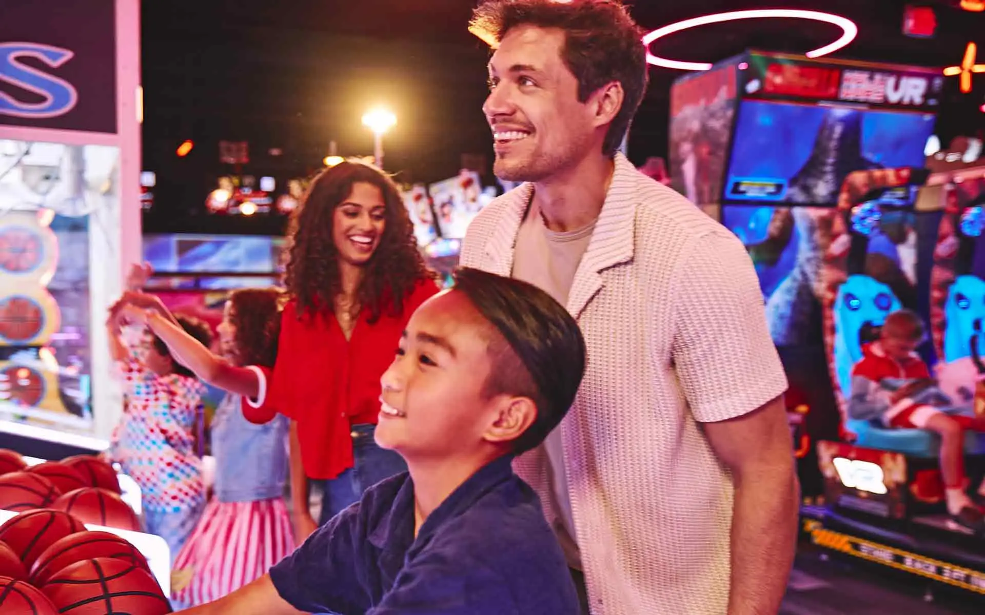 Father and son playing arcade games together at bowling entertainment center with vibrant lighting