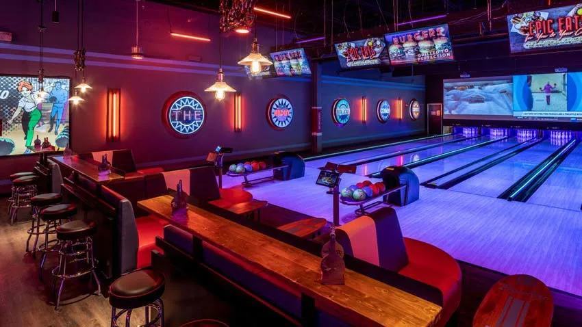 Bowling lanes at Lucky Strike Dania Beach with lounge seating, colorful bowling balls, and neon wall art