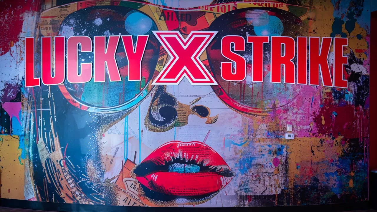Large mural of a woman's face with sunglasses and the Lucky Strike logo.