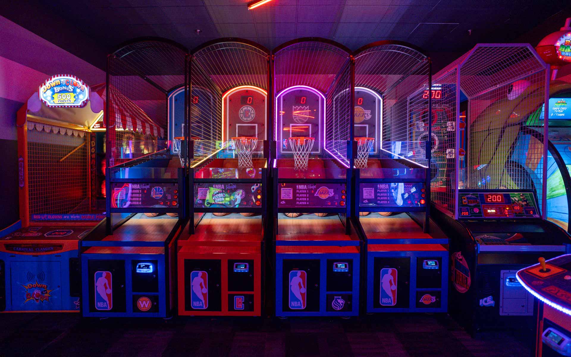 Row of illuminated basketball arcade games and classic attractions, delivering a competitive, fast-paced entertainment zone.