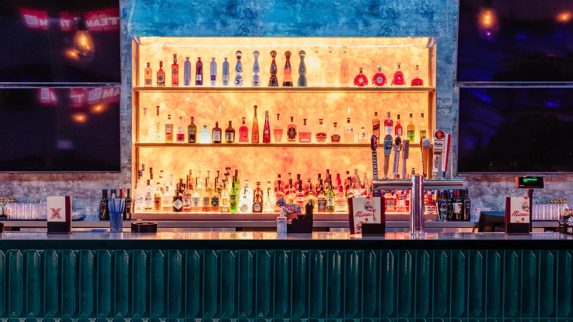 Backlit bar at Lucky Strike Aliso Viejo featuring premium liquor bottles, draft beer taps, and modern décor with a vibrant nightlife atmosphere.