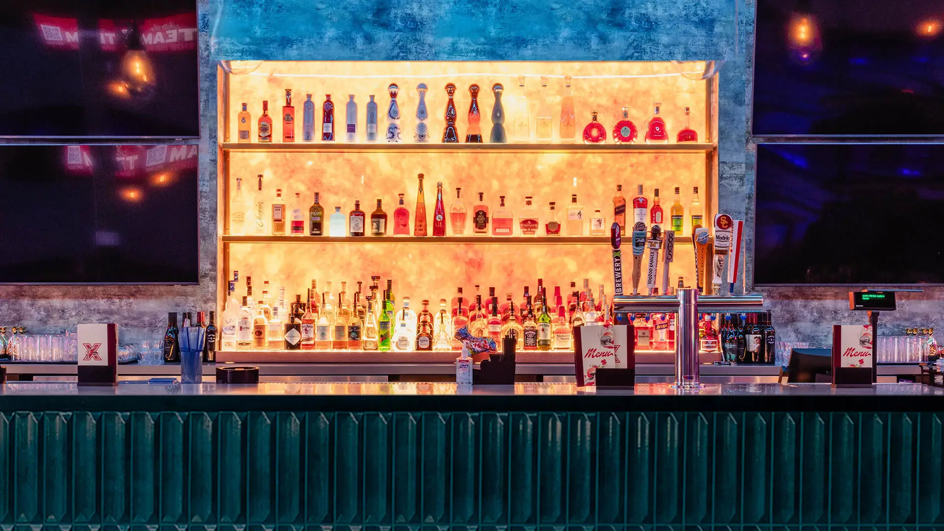 Backlit bar at Lucky Strike Aliso Viejo featuring premium liquor bottles, draft beer taps, and modern décor with a vibrant nightlife atmosphere.