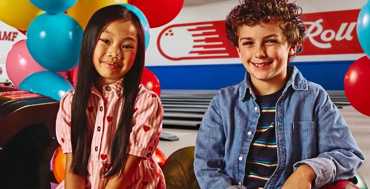 A boy and a girl sitting on top of a ball return machine at an AMF bowling center's kids party.