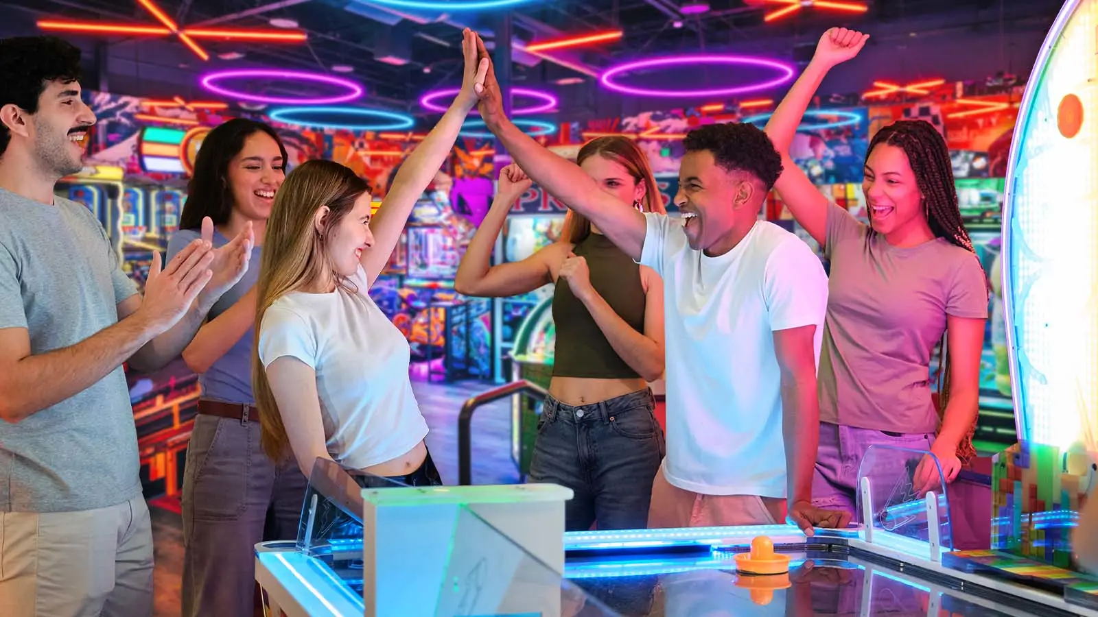 Group of teens celebrating in a large, colorful arcade