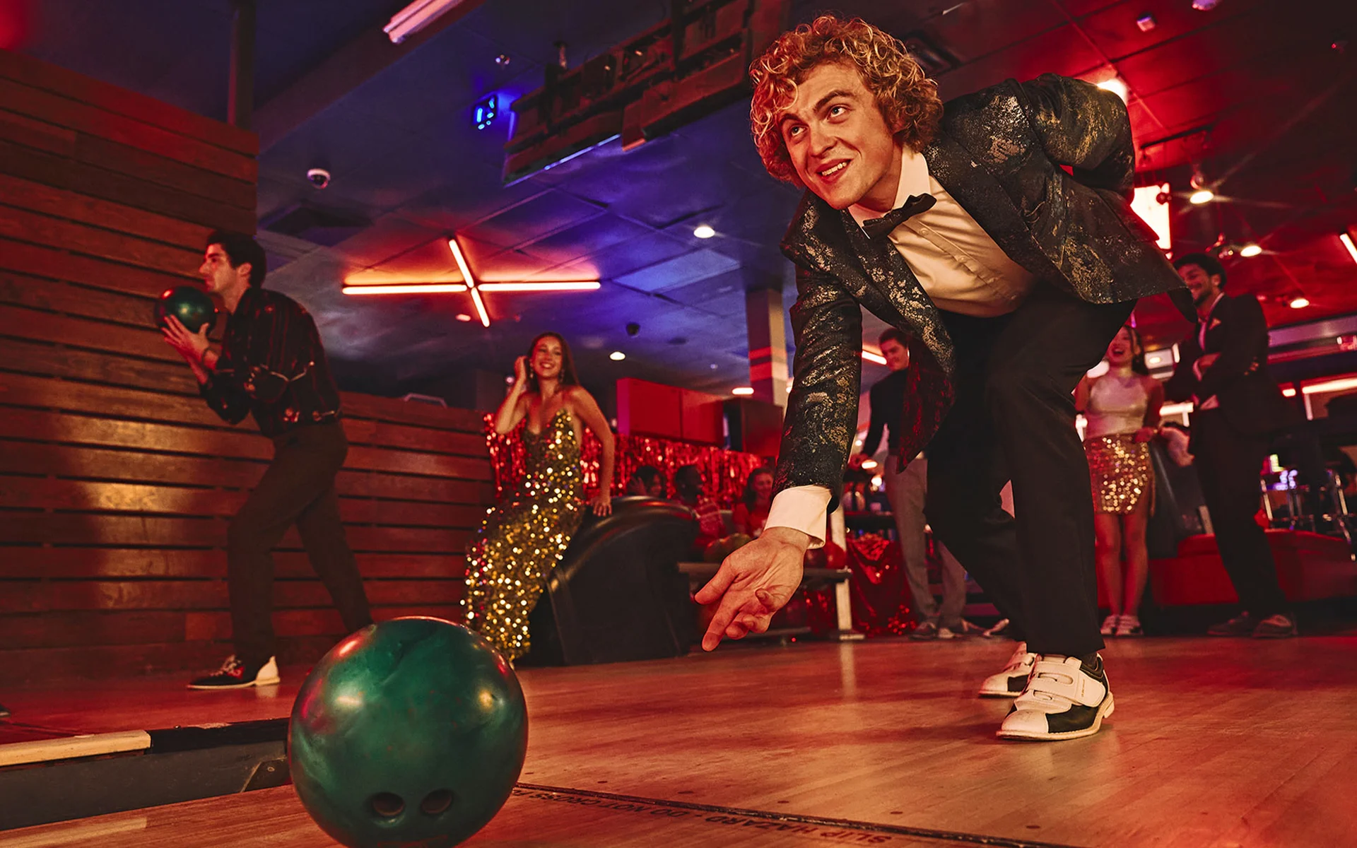 Man rolling bowling ball down lane while dressed in holiday attire