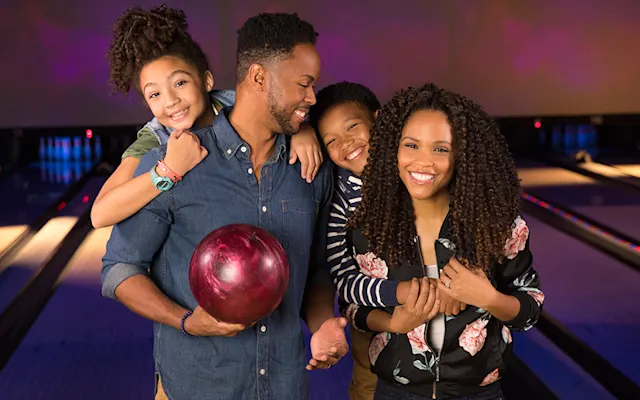 Happy family with their two children at the bowling lanes