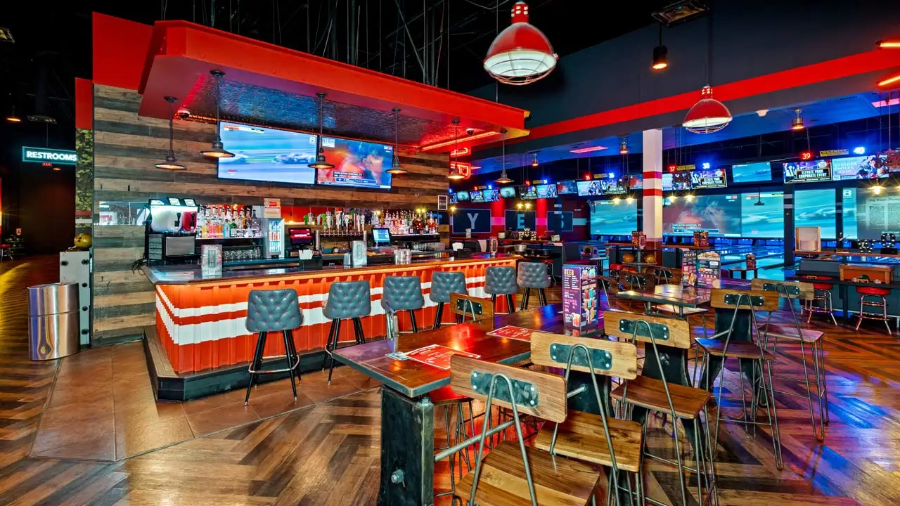 Beautiful bar with lots of seating and large TV screens above the bar.