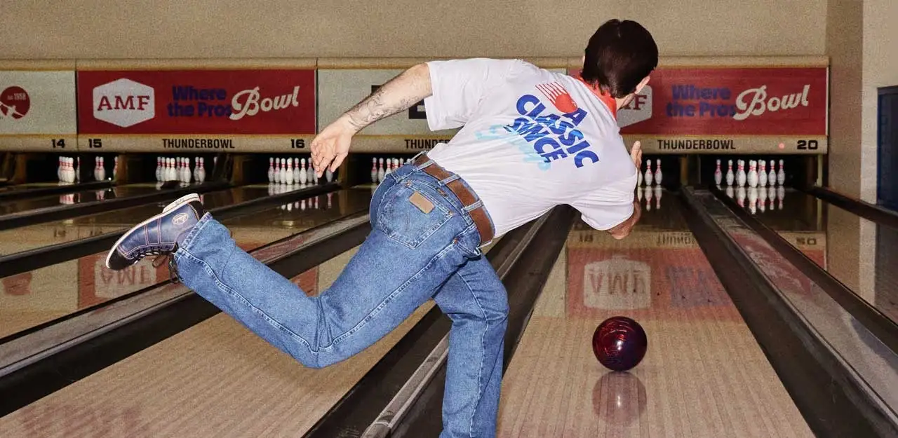 A man throwing a bowling ball down a lane at an AMF bowling center.
