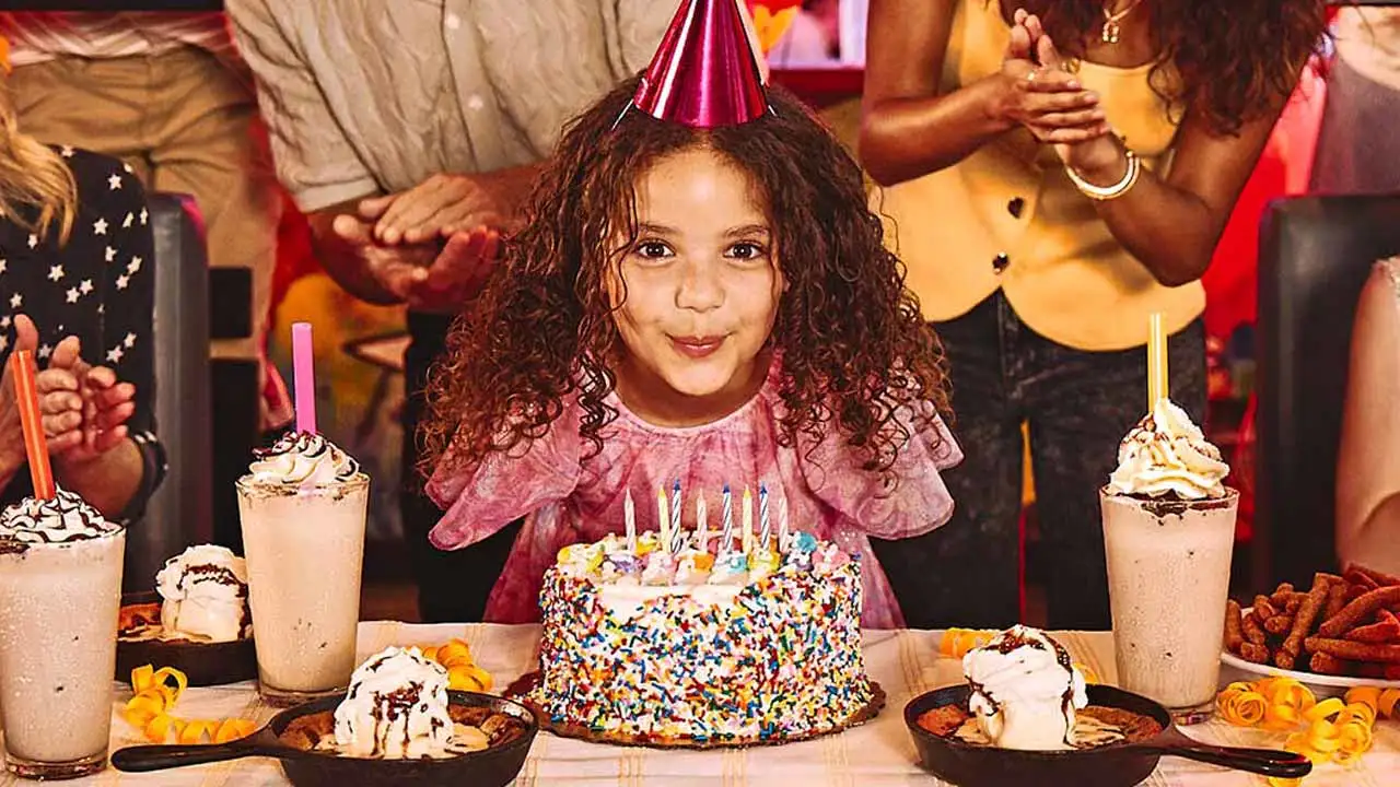 Girl blowing out candles of a birthday cake at a Lucky Strike center.