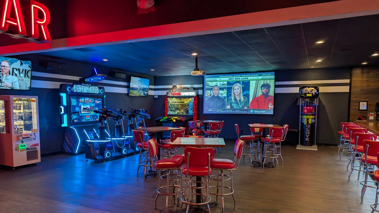 Large bar and lounge area with lots of seating and a large TV screen.