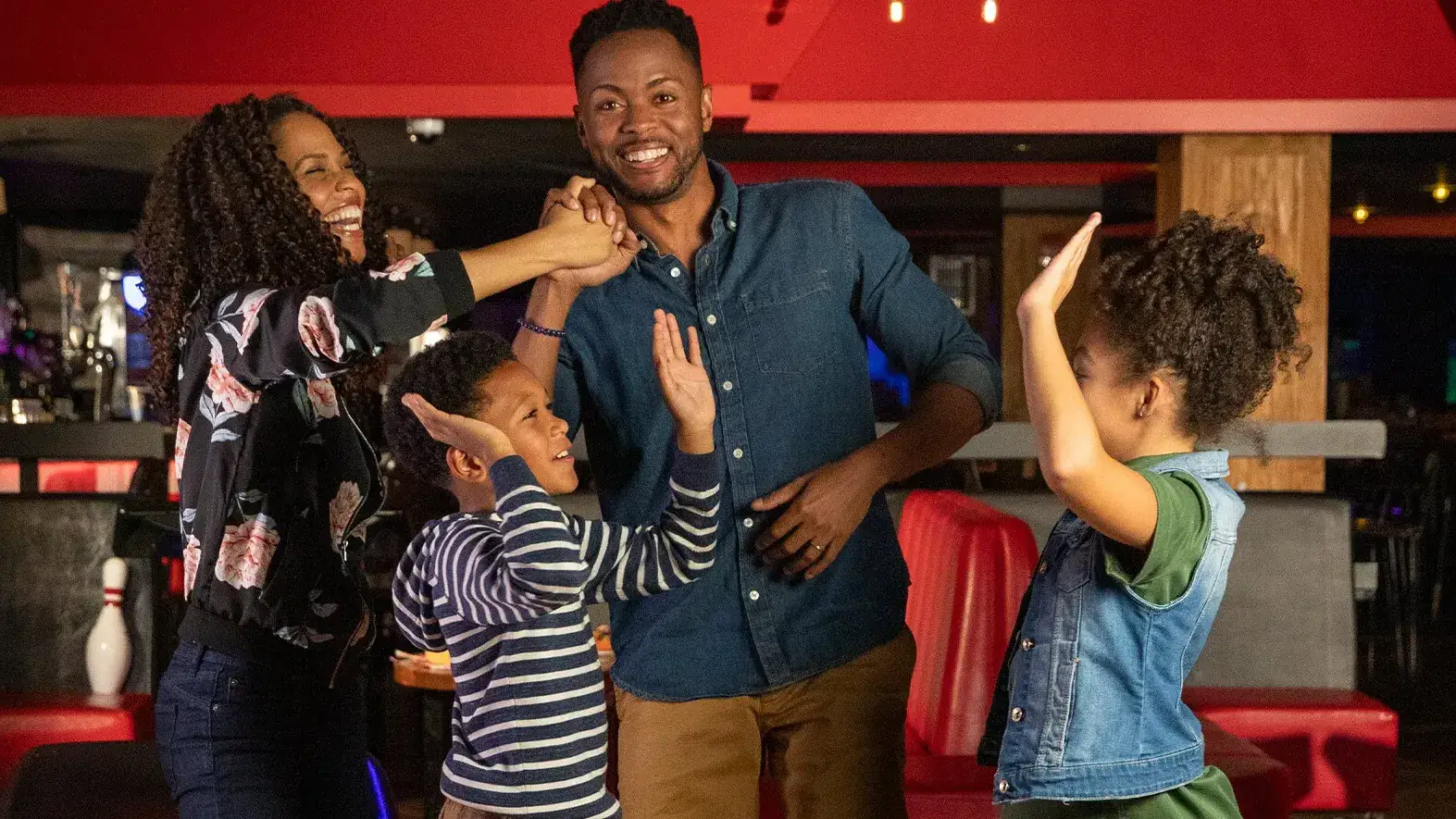 Family of four high-fiving and celebrating at a bowling center