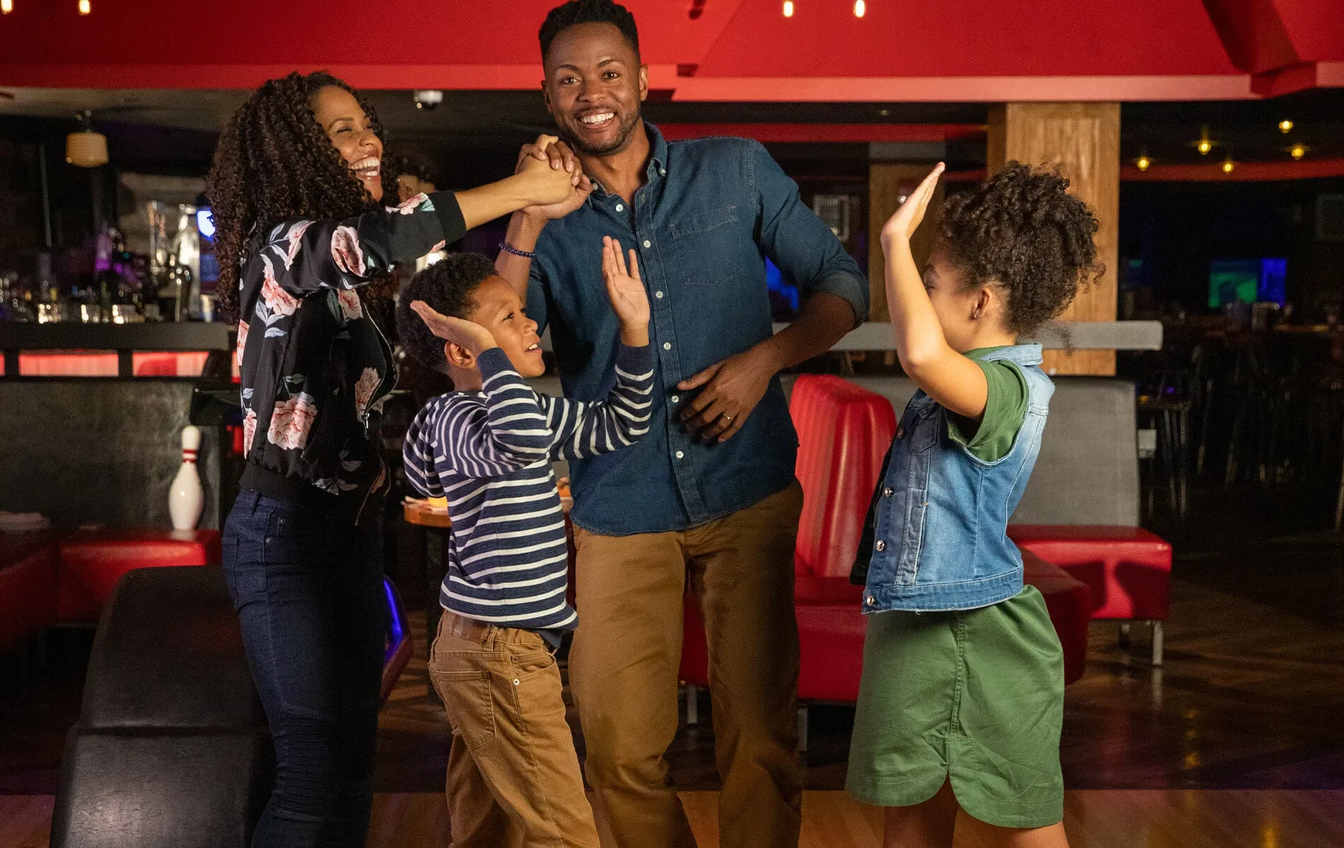 Family of four high-fiving and celebrating at a bowling center